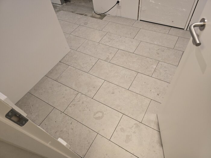 Nyfogat klinkergolv i en korridor med ljusa kvadratiska plattor, synligt från ett uppbyggnadsnåver.