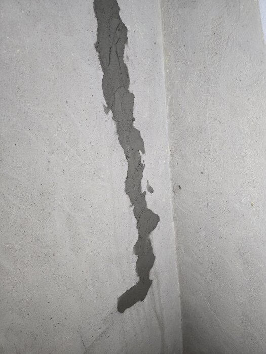 Bild av vägg med spricka som blivit fylld med lagningsbruk, för renovering och jämning av yta i ett bygge.