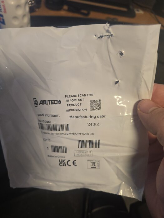 Vit plastförpackning från Aritech med hål och etiketter. Förpackningen innehöll kablar för en magnetkontakt installerad i ett fönster.