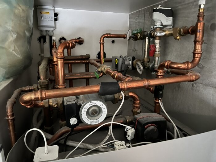 Rörsystem med kopparledningar och cirkulationspumpar, inklusive Wilo Yonos PARA RS25/6-RKA M och Grundfos UPM3 Auto L 15-70 130, i en teknisk installation.