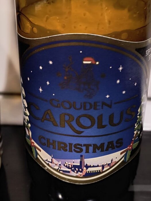 Flaska med etikett för Gouden Carolus Christmas-öl, dekorerad med vintertema och snöflingor.