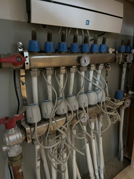 Värmesystem med cirkulationspumpar, ventiler och rörledningar, inklusive en manometer och röda och blå anslutningar.