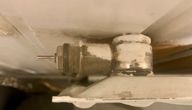 Närbild av en radiatorventil med en smal metallpinne som sticker ut, monterad på ett element utan en termostat.