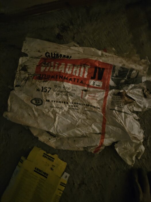 En gammal förpackning av asfaltbaserat tätskiktsmaterial, märkt "Gummifabriken Sundsvall," hittad mellan en innervägg och betong sen 70-talet.