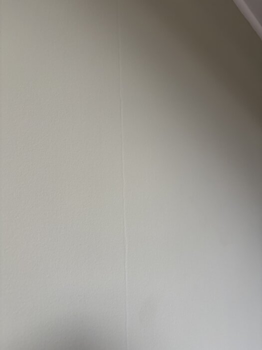 Målade väggar med synliga skarvar i dagsljus efter tapetborttagning och spackling, eventuellt på grund av bristande förarbete.