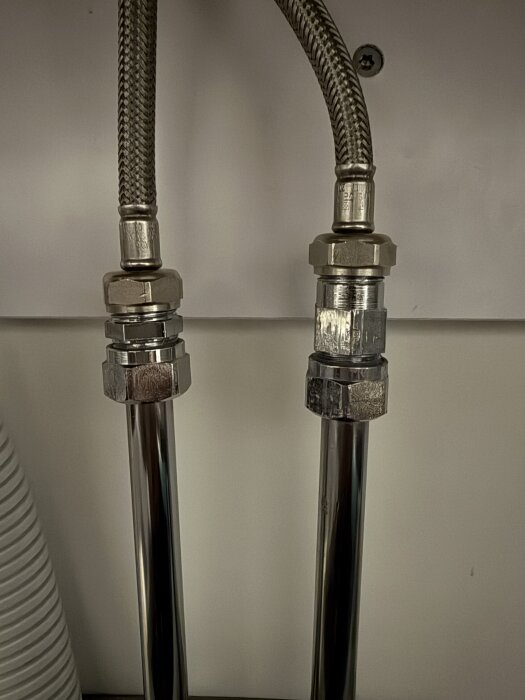 Två installerade metallslangar med kopplingar i ett VVS-projekt.