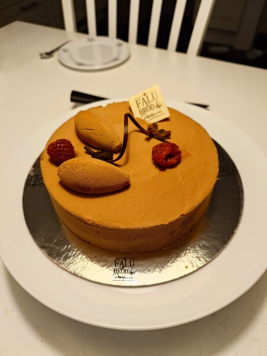 Chokladmoussetårta med hallon och maräng dekorerad med hallon och choklad på ett vitt fat.