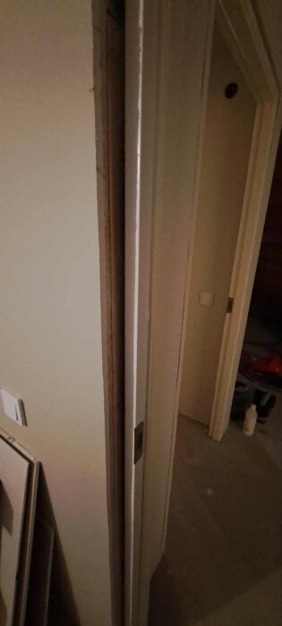 Nyinstallerad innerdörr med karm syns mot en vägg med renoveringsgips, en kant på 6-10 mm är tydlig längs sidan av dörröppningen.