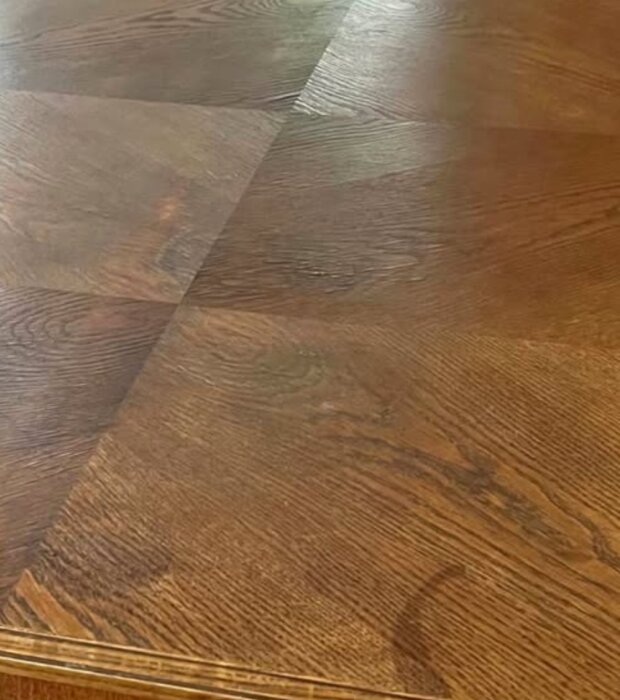 Bilden visar en bordsskiva med mörkt trä och tydlig ådring, eventuellt ek, fotograferad i ett matsalsprojekt.