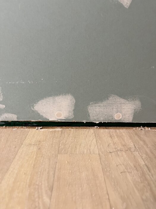 Glipa mellan vägg och golv med synliga håligheter, där masonitskivor har tagits ner i ett renoveringsprojekt.