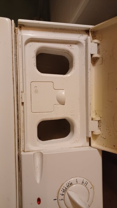 Öppen vit lucka på tvättmaskin med två fack och rött vred.