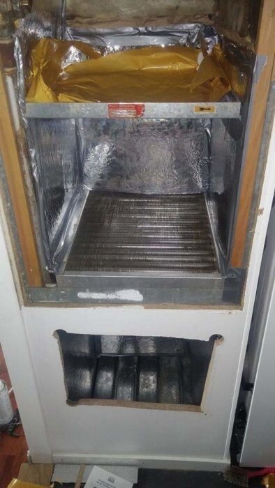 Öppning i vägg där en frånluftsfläkt tidigare satt, med synlig metallkanal och isolering.