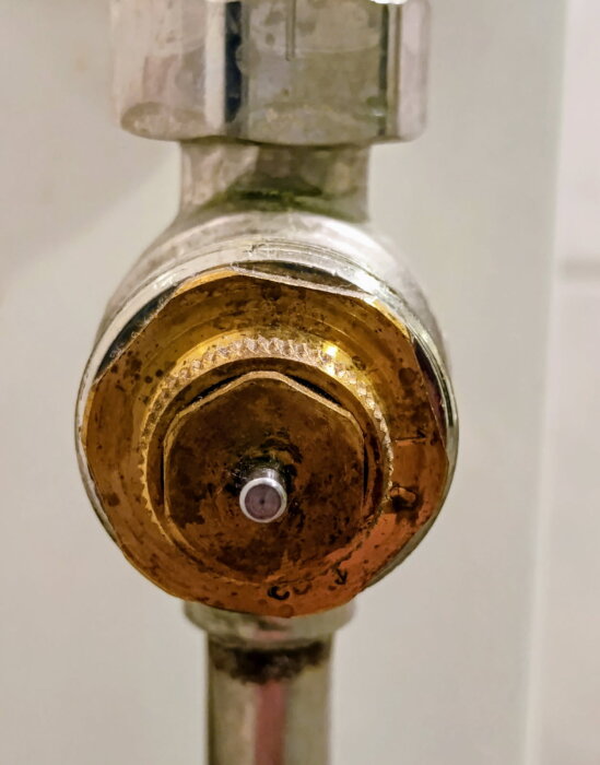 Ventil i huset saknar termostat, nära bild på justeringsdel i metall.