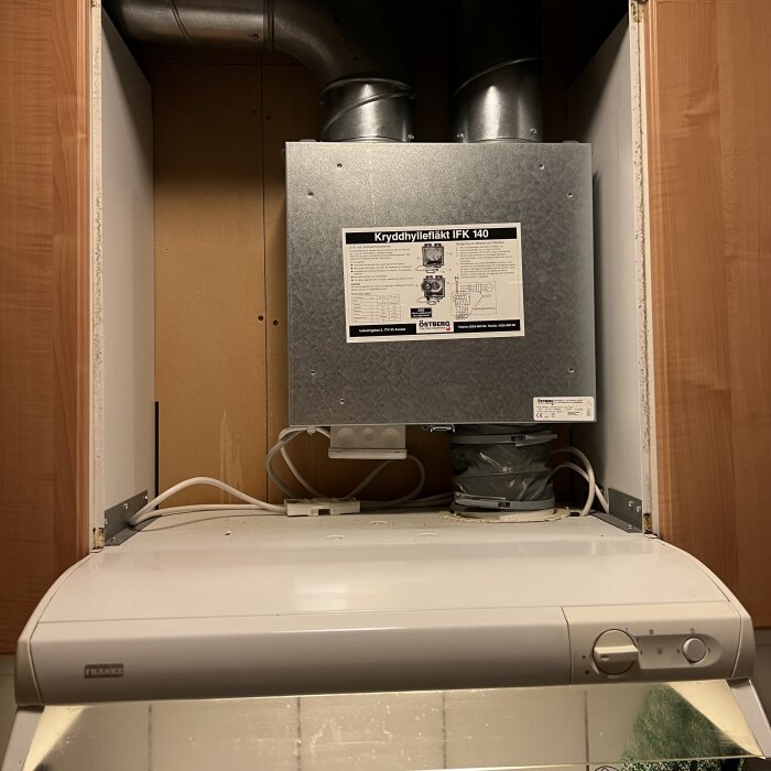 Spiskåpa med ventilationssystem och fläkt i köksskåp, märkt "Kryddhyllefläkt IFK 140" från Östberg.