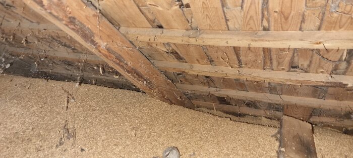 Vind med träbjälklag och synliga spån som isolering under taket.