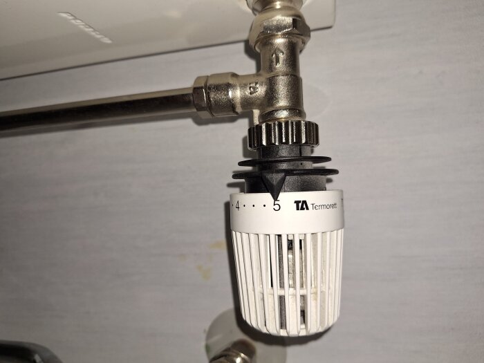 Danfoss TA-termostat ansluten till en radiator, inställd på nivå 5. Sökes information om modell och demonteringsinstruktioner.