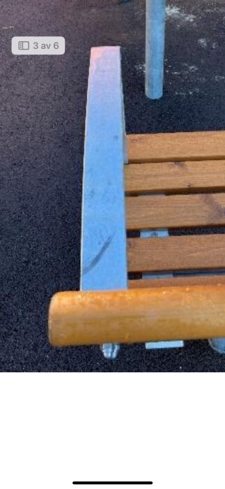 Träbänk med metallram på mörk mark.