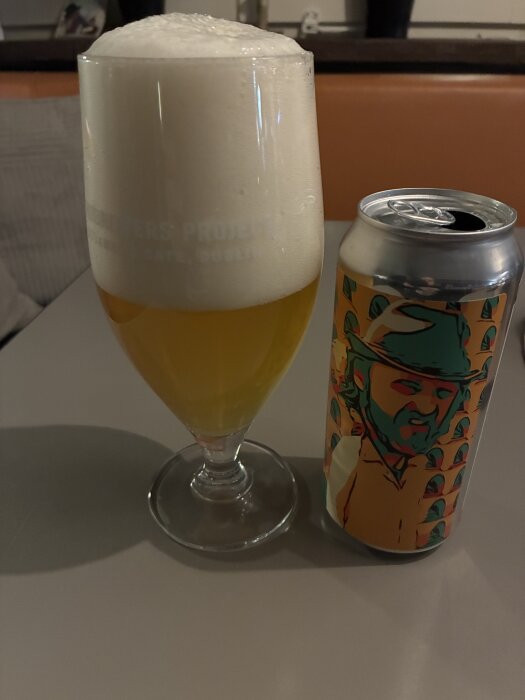 Ett glas öl med skummande topp bredvid en färgglad burk från Nyköpings Brewery, redo för kvällens musikquiz.