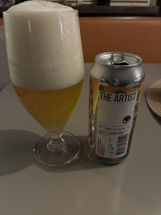 Ölglas med skum bredvid en burk av ölsorten "The Artist" från Nyköpings Brewery, på ett bord inför kvällens musikquiz.