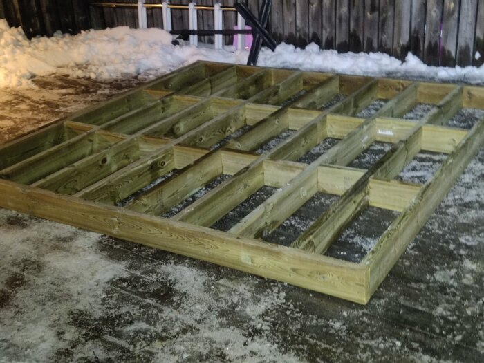 Stomme av träreglar för altanbygge på snötäckt mark.