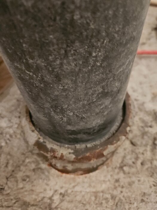 Gjutjärnsrör inbäddat i betonggolv, med frågeställning om ventilering och lukt mellan plaströr och gjutjärn.