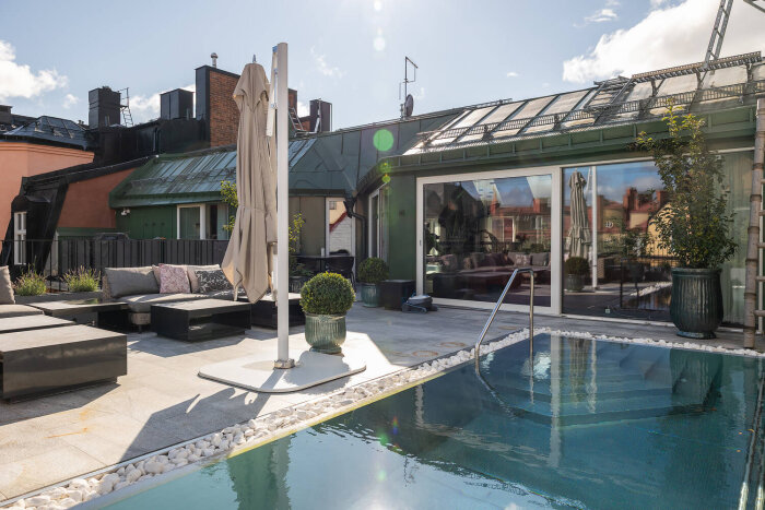 Takvåning med pool och sittgrupp invid Karlaplan, soligt väder och moderna omgivningar.