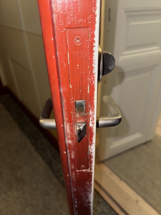 Röd pardörr med synligt dörrlås och handtag, i fokus för diskussion om att installera Yale Doorman-lås.