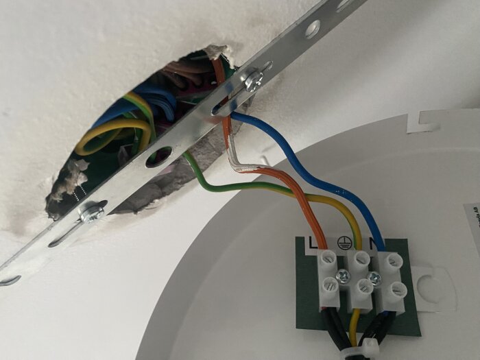 Elektrisk installation med färgkodade kablar anslutna till en kopplingsplint vid taket, för dubbelkoll av korrekt anslutning.