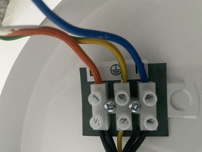 Elanslutning med kopplingsplint och kablar i olika färger: blå, gul, grön, brun. Kontrollera korrekt installation.