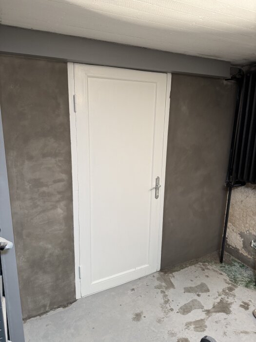 Vägg med nyputsad yta runt en vit dörr, med jämn finish tack vare användning av combimix cm 850.