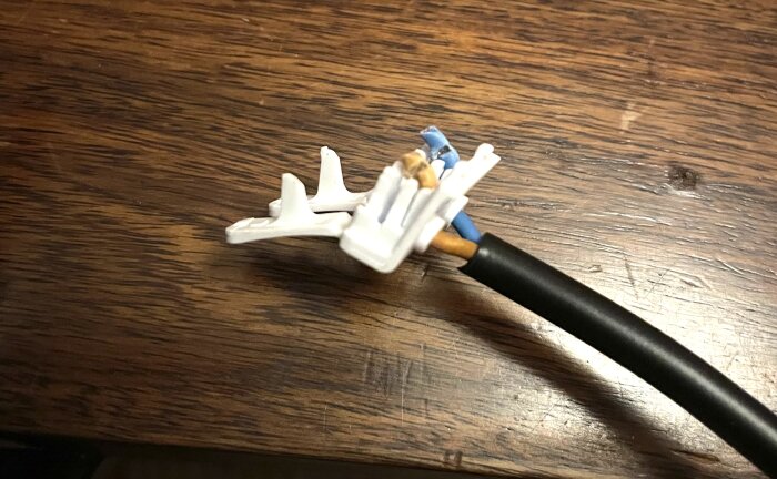 En samling sladdar med vita plastflärpar på en träyta, del av ett byggprojekt.