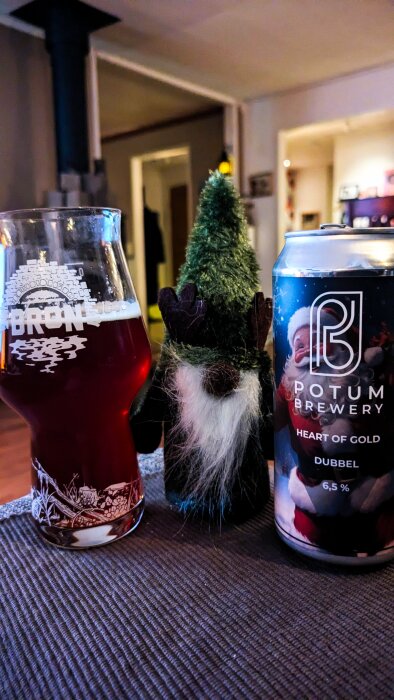 Ölglas med rödbrun dryck, julölburk från Potum Brewery och juldekoration i form av en tomte framför en kamin.