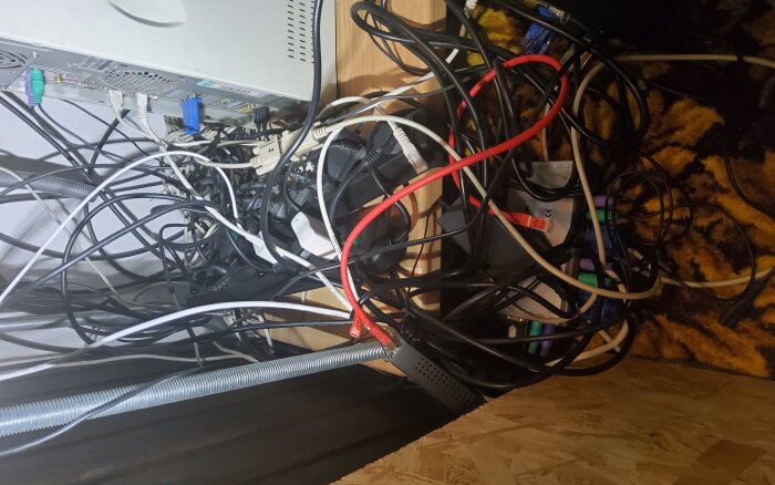 Kabeltrassel bakom datorn i filmrummet, med sladdar från olika enheter och kontakter huller om buller.