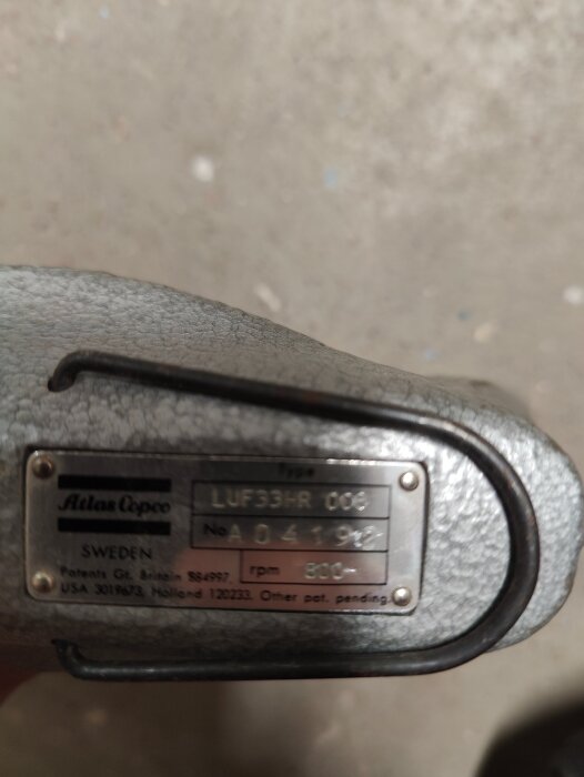 En grå metallmaskin med en typskylt från Atlas Copco, där det står "LUF33HR 008" och "800 rpm".