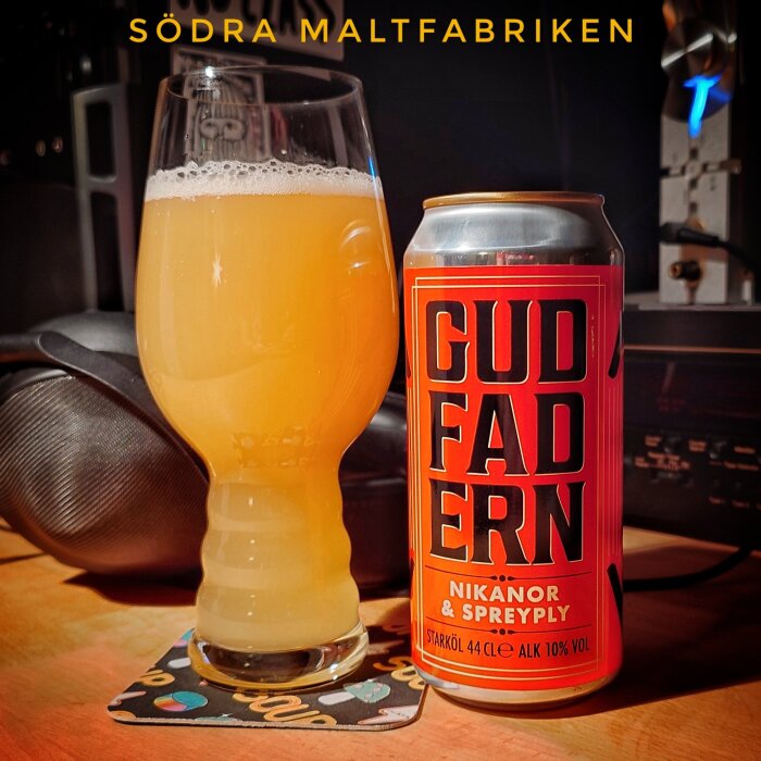 En burk och ett glas öl på ett bord, etiketten visar "Gudfadern" från Södra Maltfabriken.