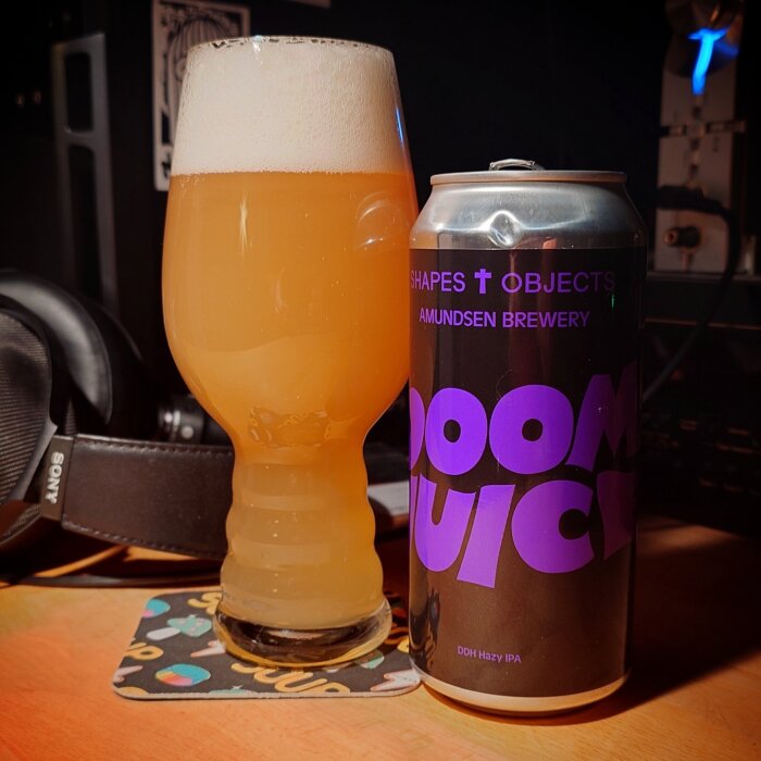 Ett glas fyllt med ljus öl bredvid en burk märkt "Doom Juice" från Amundsen Brewery.