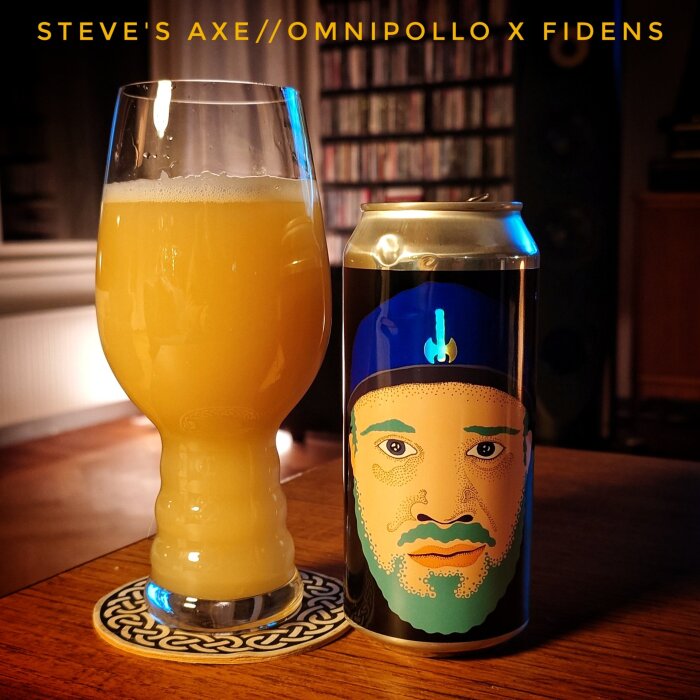 Ölglas fyllt med ljus öl bredvid en burk med färgglad illustration på ett ansikte, placerat på ett träbord.