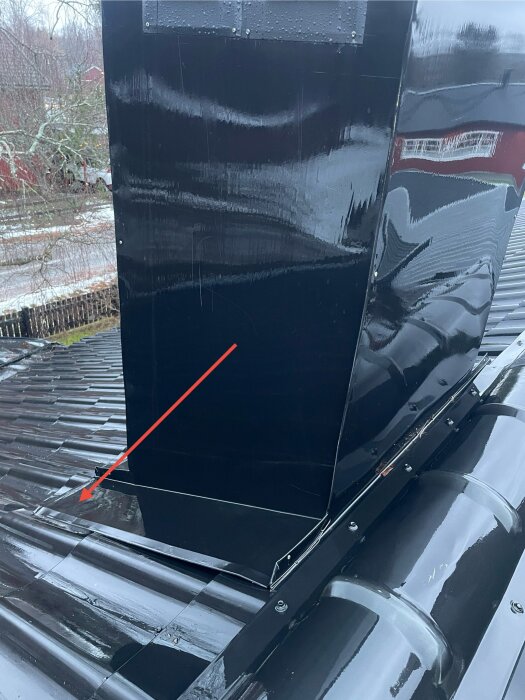 Ventilationshuv på plåttak med en pil som pekar mot potentiellt fuktproblem vid genomföringen.