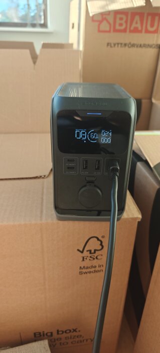 Bärbar generator med display på kartong, visar laddningsstatus. Försöker använda solpaneler under november.