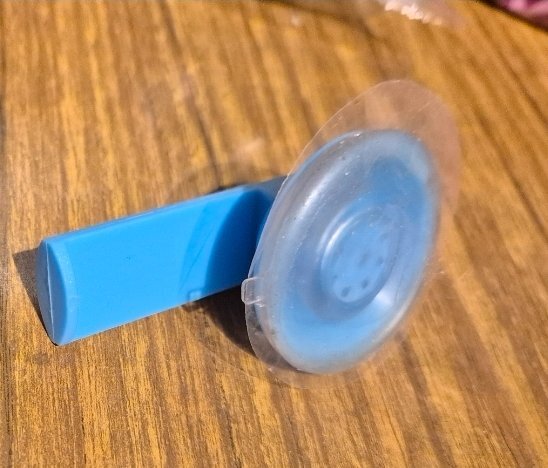 Blå sugkopp med plasthandtag ligger på ett trämönstrat underlag, rekommenderad för bättre grepp enligt inlägg i diskussionstråd.