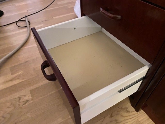 Öppen nedersta låda i ett brunt Timanttiskåp, visar problemet med att inte kunna stängas helt, med synlig skena och skruv på sidan.