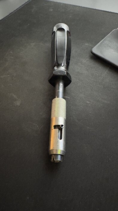 Robust, omärkt verktyg med svart handtag och metallfäste, möjlig säkerhetsfattning för belysningsstolpe.