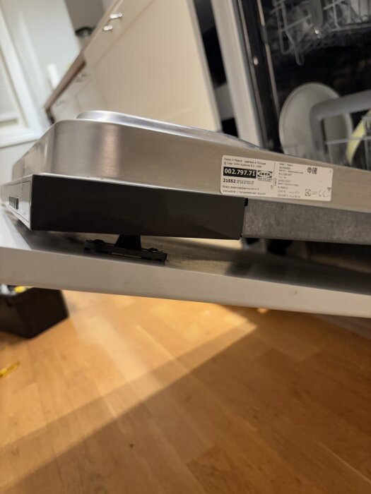 Öppen diskmaskin med vit frontdel borttagen för att visa inbyggd panel och etikett med produktinformation från IKEA.