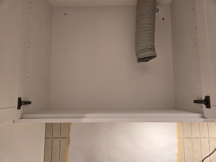 Inuti köksskåpet med fläktkanal och ljusspotpanel under två 90cm skåp.