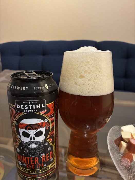 En ölburk med Destihl Brewery Winter Red IPA och ett glas fyllt med skummande öl, bredvid en skål med ost och korv.