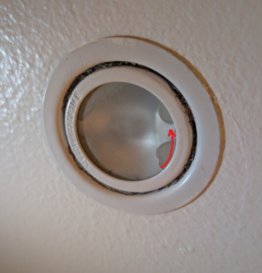 Bajonettfattning på lampa med antydan av pil som visar vridriktning.