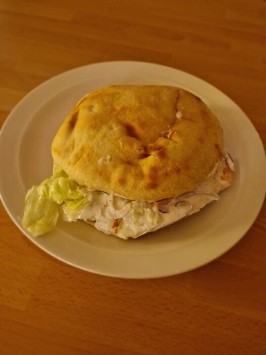 Kycklingkebab med bröd och sallad serverad på en vit tallrik.