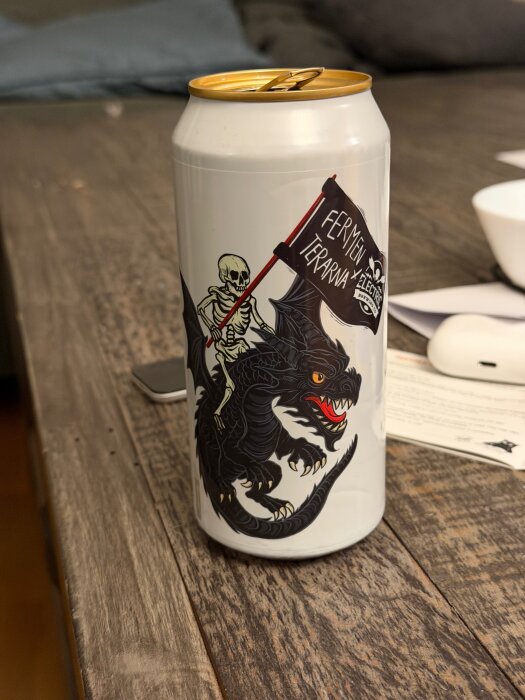 En ölburk med en illustration av en skelettfigur som rider på en svart drake och håller en flagga med texten "Fermen terrarna x Electric".