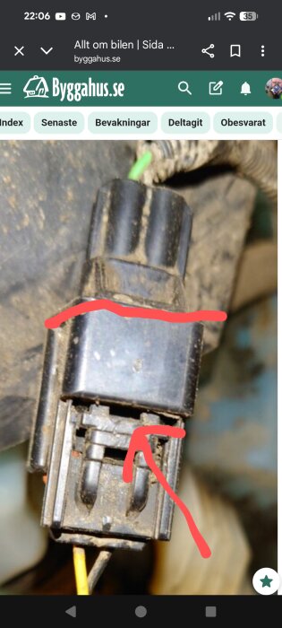 Delbart kontaktstycke från bil med röda markeringar som visar delningslinje och spärr för isärtagning.