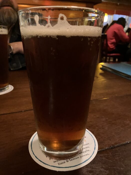 Ett glas rött öl, benämnt "Aruba red", står på ett bord i en pubmiljö.